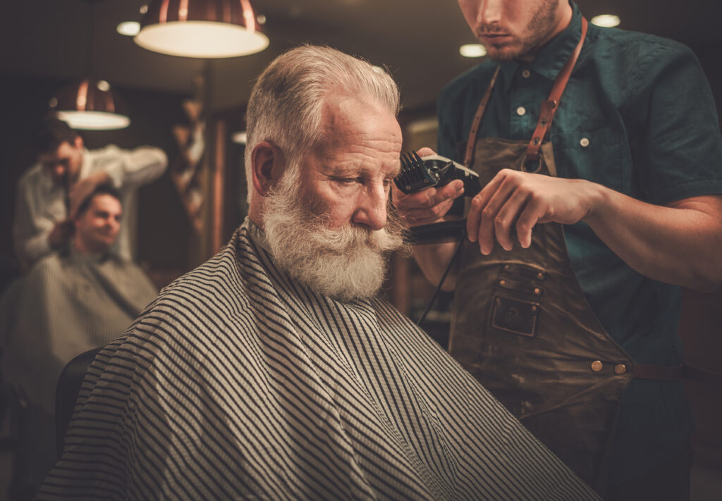 Confident senior man visiting hairstylist in barber shop.