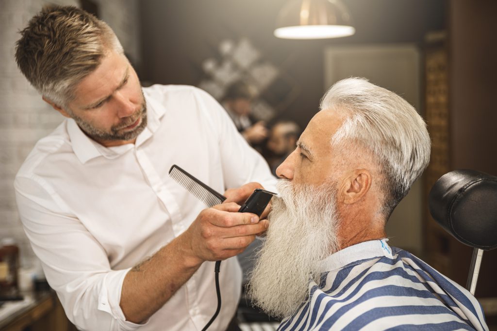 Handsome senior man getting styling and trimming of his beard